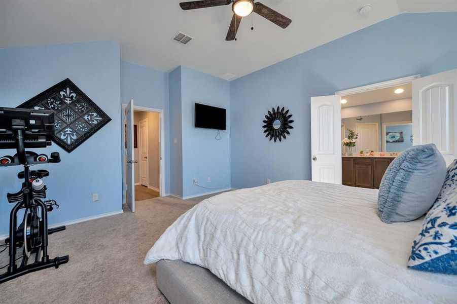 Bedroom featuring lofted ceiling, light colored carpet, a ceiling fan, and ensuite bathroom