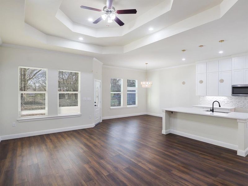 Unfurnished living room with ceiling fan, dark wood-style flooring, recessed lighting, and crown molding Unfurnished living room with ceiling fan, dark wood-style flooring, recessed lighting, and crown molding