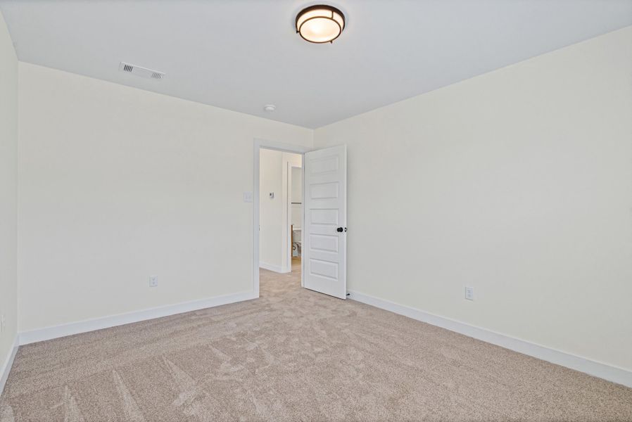 Neutral-toned room featuring a five-panel interior door, ceiling-mounted light fixture, and plush carpet flooring Neutral-toned room featuring a five-panel interior door, ceiling-mounted light fixture, and plush carpet flooring