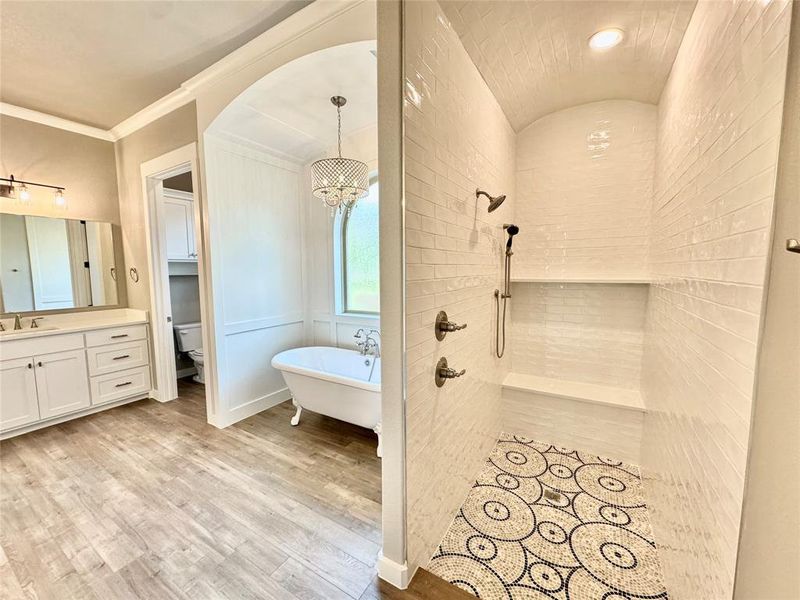 Primary bathroom featuring vanity, toilet, ornamental molding, hardwood / wood-style flooring, and independent shower and bath