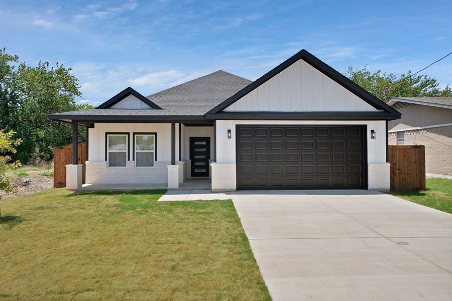 View of front of house featuring a garage, concrete driveway, brick siding, a shingled roof, and board and batten siding