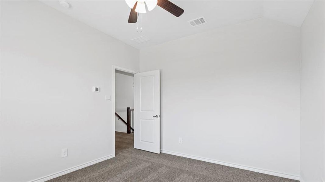Carpeted room with vaulted ceilings and a ceiling fan