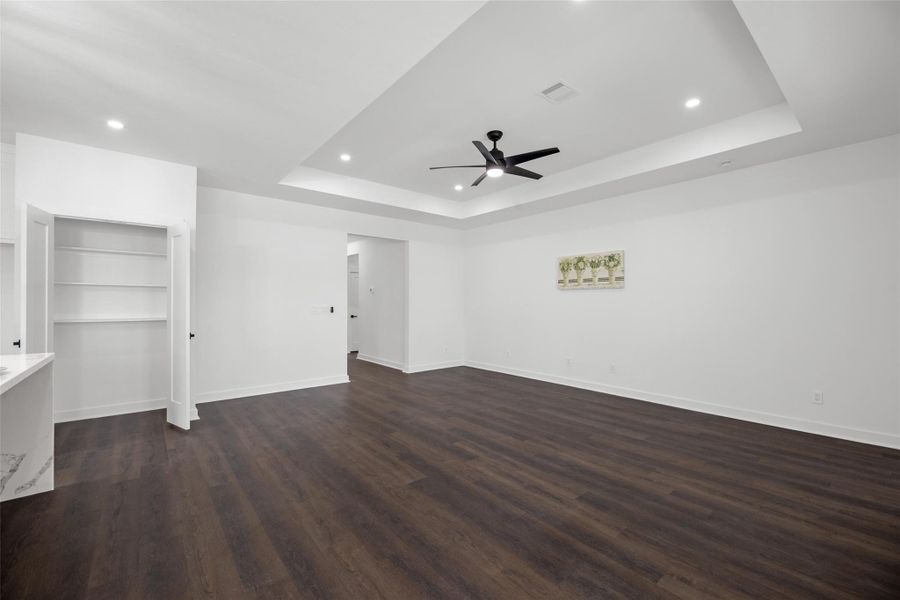 Tray ceiling with recessed lighting that includes a modern ceiling fan, open shelving, and neutral walls for easy personalization.