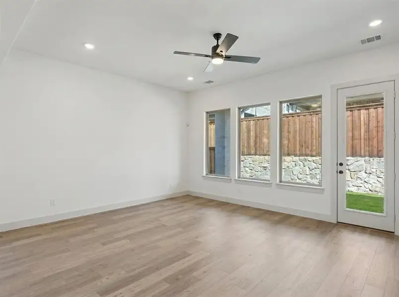 Spacious room featuring light wood-finish flooring, recessed lighting, and a modern ceiling fan