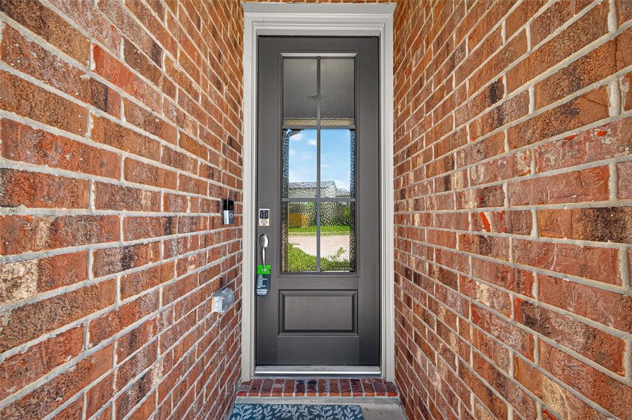 Charming brick entryway showcases a modern black door with glass panels, offering a welcoming first impression.