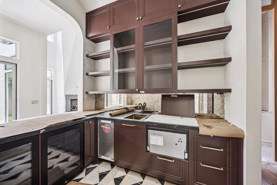 Fantastic Wet-Bar area located between the Formal Dining Room and Island Kitchen. There is Sink, Wine Refrigerator, Panel-Ready Ice Maker and a Panel Ready Fisher and Paykel Series 9, Integrated Single DishDrawer Dishwasher.  There are custom painted inset cabinetry, antique mirror backsplash, tile floor and more.