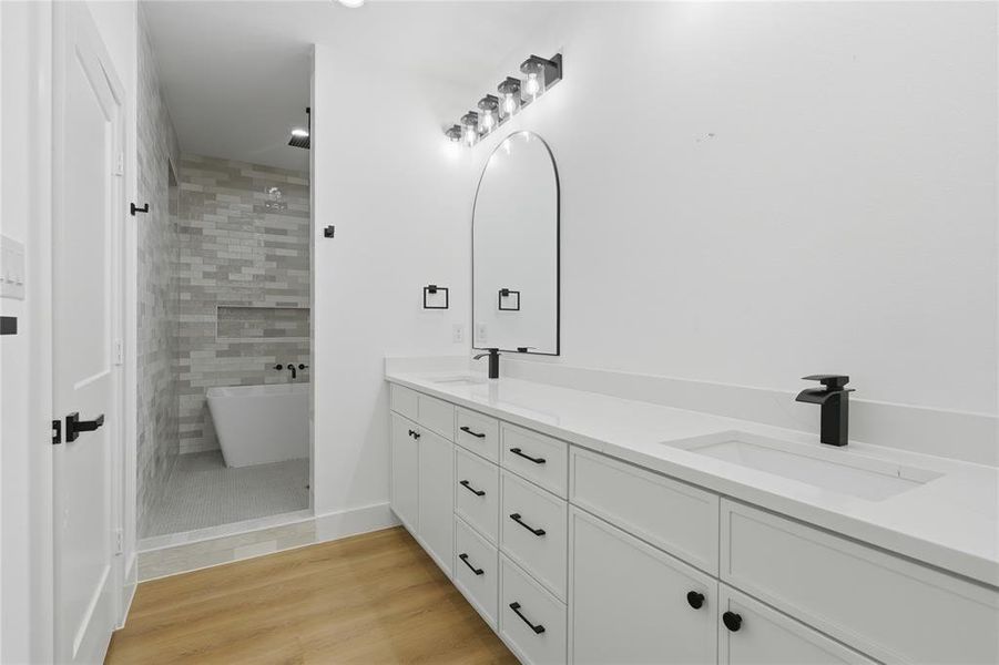 Spacious bathroom with dual vanities featuring white cabinetry, integrated sinks, and matte black fixtures Spacious bathroom with dual vanities featuring white cabinetry, integrated sinks, and matte black fixtures