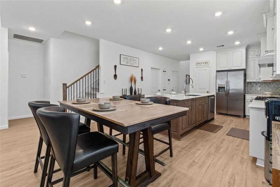 Bright and modern kitchen featuring a large center island with a farmhouse sink, sleek stainless steel appliances, and ample cabinetry, complemented by a stylish dining area with contemporary seating. Bright and modern kitchen featuring a large center island with a farmhouse sink, sleek stainless steel appliances, and ample cabinetry, complemented by a stylish dining area with contemporary seating.