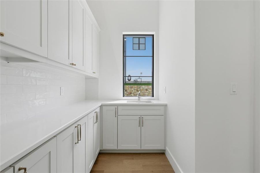 White shaker-style cabinetry with gold-tone hardware, white subway tile backsplash, and light-tone countertops