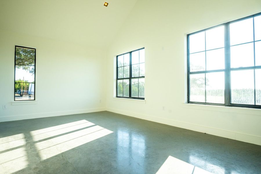 Unfurnished room featuring high vaulted ceiling and concrete floors