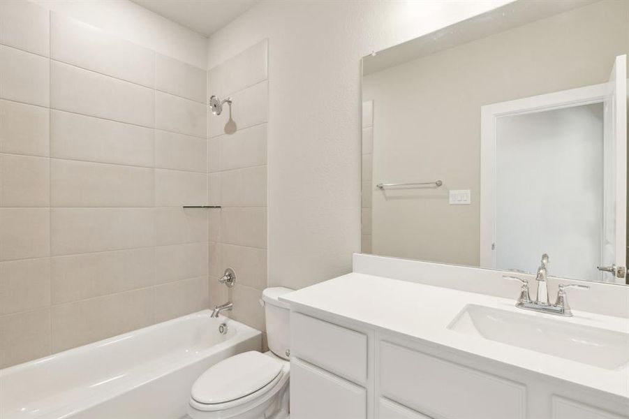 Full bathroom with tiled shower / bath combo, toilet, and vanity