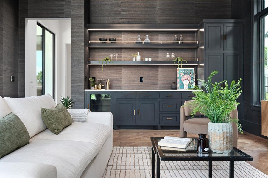 Elegant living area featuring a built-in wet bar with illuminated shelving and rich wood flooring.