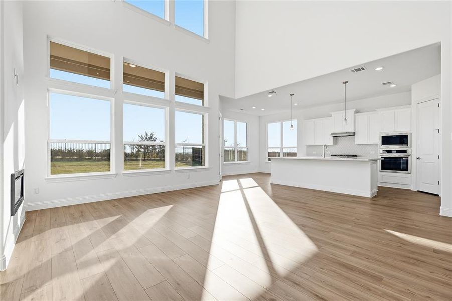 Unfurnished living room featuring light wood-style flooring, a high ceiling, and recessed lighting Unfurnished living room featuring light wood-style flooring, a high ceiling, and recessed lighting