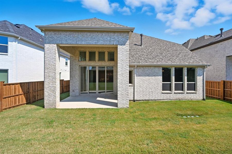 Back of house with brick siding, a patio area, a fenced backyard, and roof with shingles