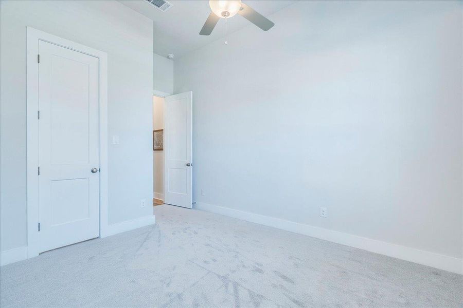 Unfurnished bedroom featuring light carpet and ceiling fan Unfurnished bedroom featuring light carpet and ceiling fan