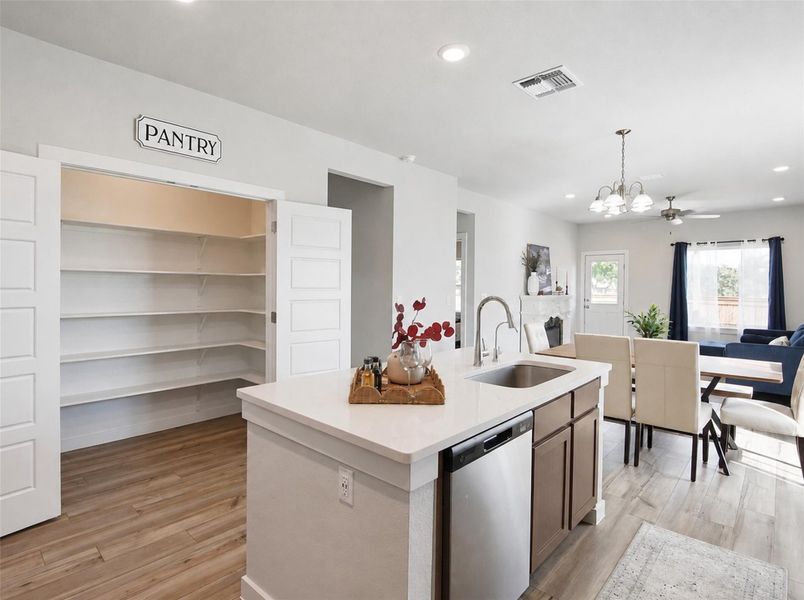 A spacious walk-in pantry stands adjacent to a modern kitchen island with integrated sink. A spacious walk-in pantry stands adjacent to a modern kitchen island with integrated sink.