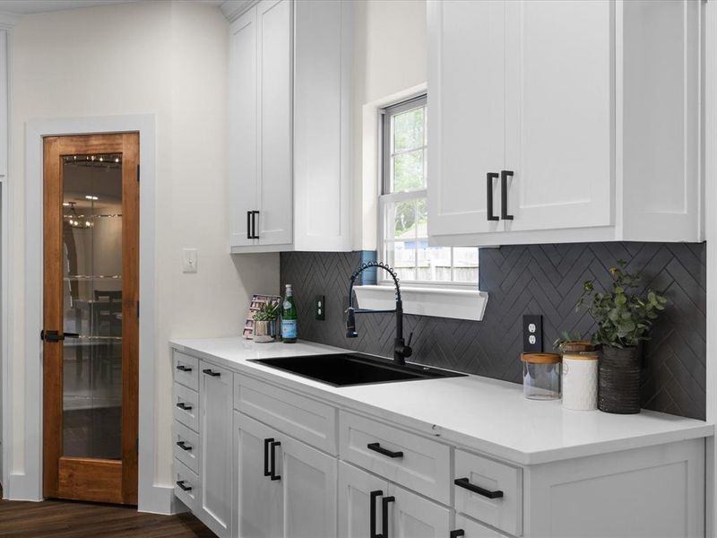 Kitchen featuring white cabinetry, light stone counters, dark wood-style floors, and decorative backsplash