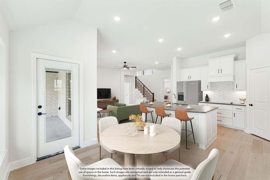 Open-plan dining area and kitchen with white cabinets, island seating, and light hardwood floors