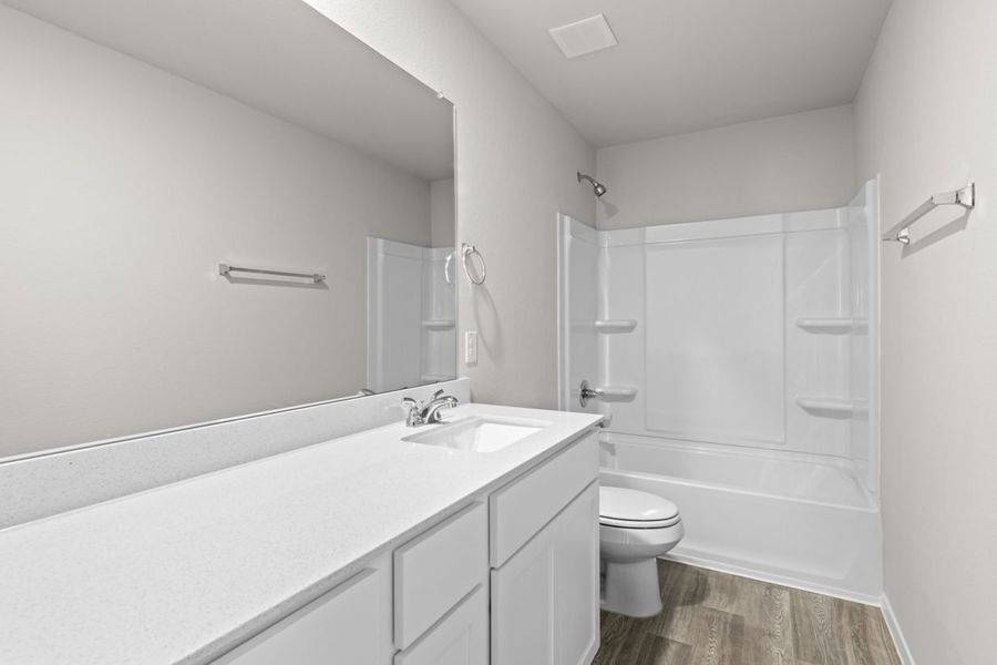Image of a bathroom with a white dual vanity, white cabinets, a large mirror, and a white shower ILO tub