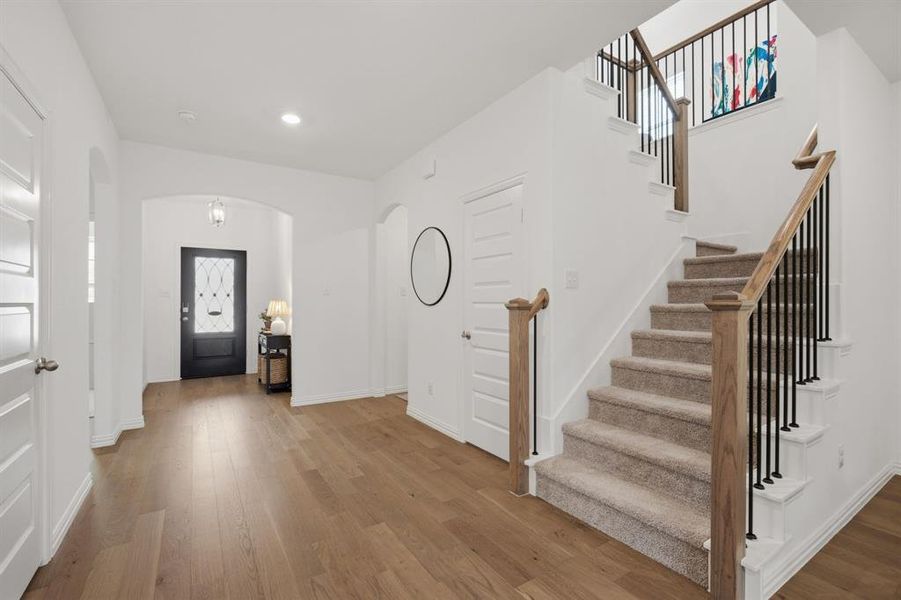 Welcoming entry with arched detail, wide hallway, and beautiful real wood flooring. The first impression feels bright, clean, and move-in ready.