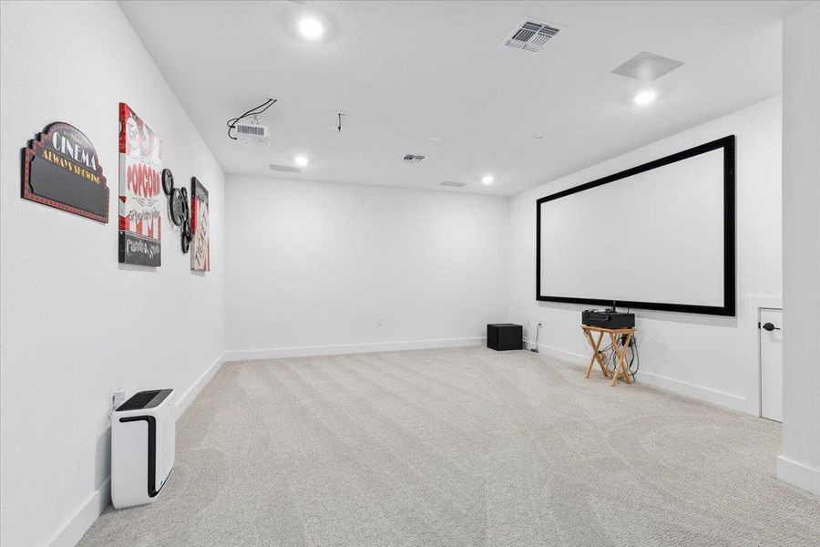 Carpeted home theater with recessed lighting and baseboards