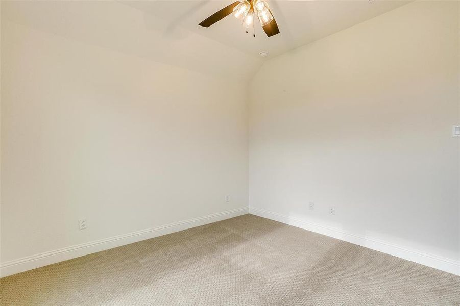 Carpeted empty room with lofted ceiling and ceiling fan