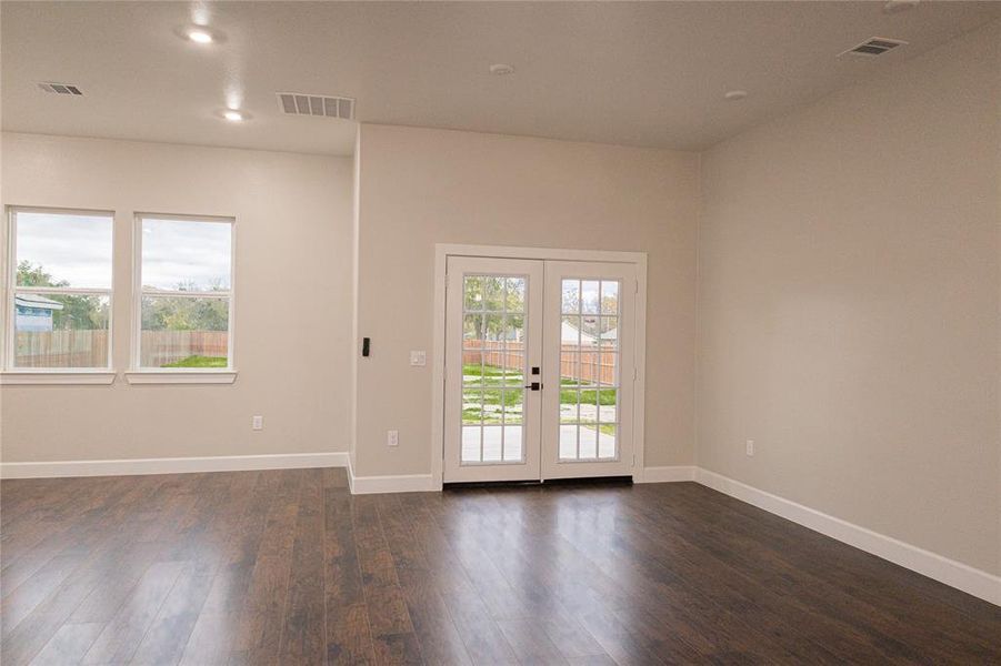 Empty room featuring healthy amount of natural light, recessed lighting, dark wood-style floors, and french doors Empty room featuring healthy amount of natural light, recessed lighting, dark wood-style floors, and french doors