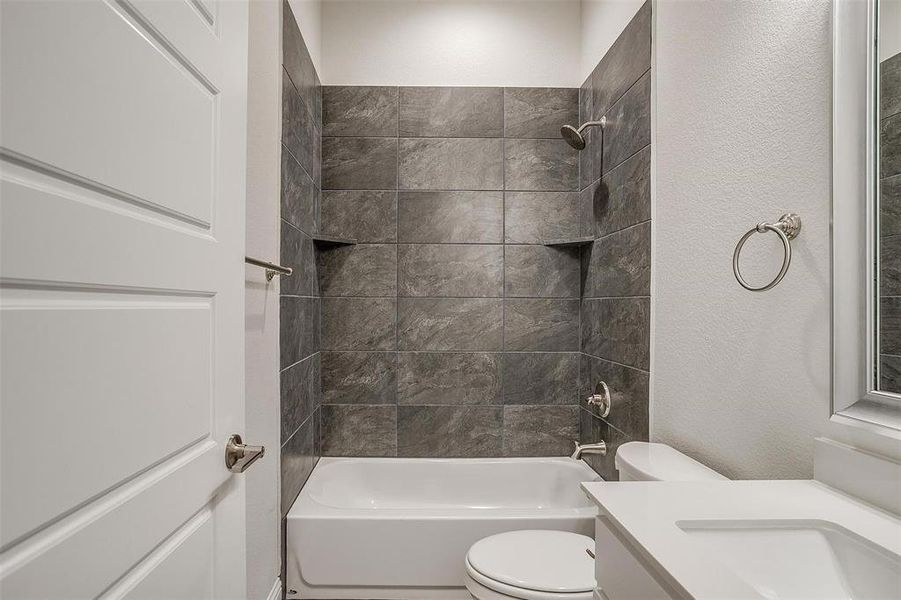 Full bathroom with toilet, vanity, and tiled shower / bath