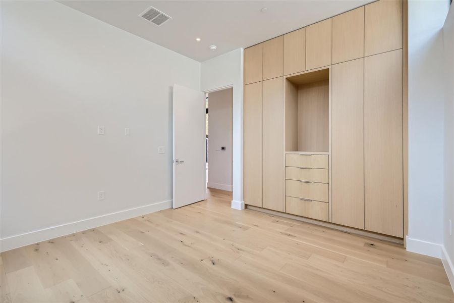 Minimalist design and light wood flooring define this serene bedroom, offering built-in storage solutions. Minimalist design and light wood flooring define this serene bedroom, offering built-in storage solutions.