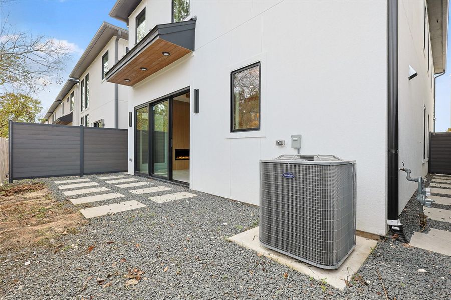 The outdoor space consists of a low-maintenance gravel yard with geometric concrete pavers leading to a large sliding glass door.