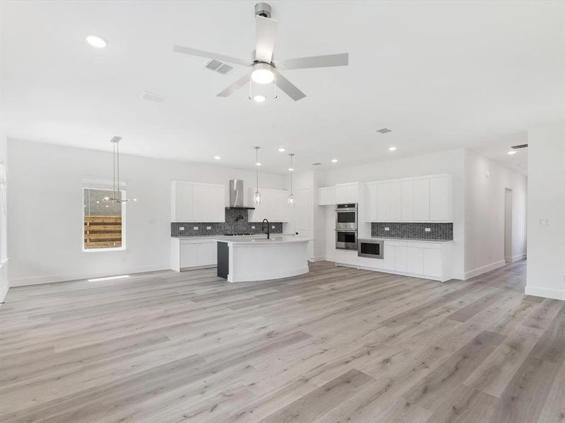 Unfurnished living room featuring light wood finished floors, ceiling fan, and recessed lighting
