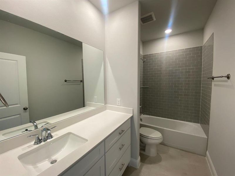 Full bathroom with toilet, vanity, and tiled shower / bath