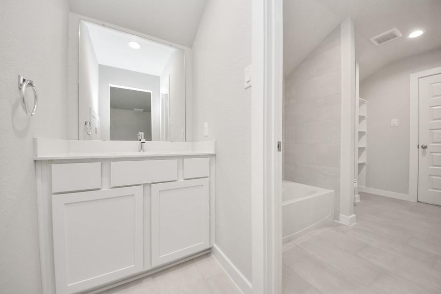 Experience convenience in the secondary bathroom, designed for Jack and Jill arrangements, now with a separate vanity area. This well-appointed space showcases stylish tile flooring, a bath/shower combo with an elegant tile surround, and light-stained wood cabinets. The beautiful light countertop adds a touch of sophistication, combining functionality and aesthetics seamlessly. Sample photo of completed home with similar floor plan. Actual colors and selections may vary. Experience convenience in the secondary bathroom, designed for Jack and Jill arrangements, now with a separate vanity area. This well-appointed space showcases stylish tile flooring, a bath/shower combo with an elegant tile surround, and light-stained wood cabinets. The beautiful light countertop adds a touch of sophistication, combining functionality and aesthetics seamlessly. Sample photo of completed home with similar floor plan. Actual colors and selections may vary.