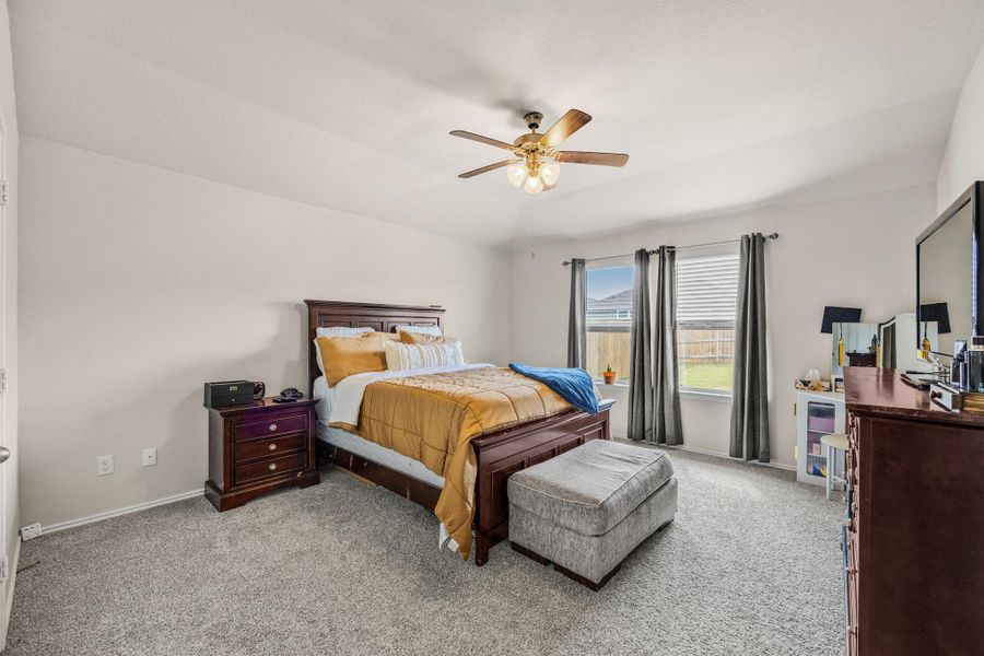 A restful bedroom with soft carpet flooring and a refreshing ceiling fan for comfort.