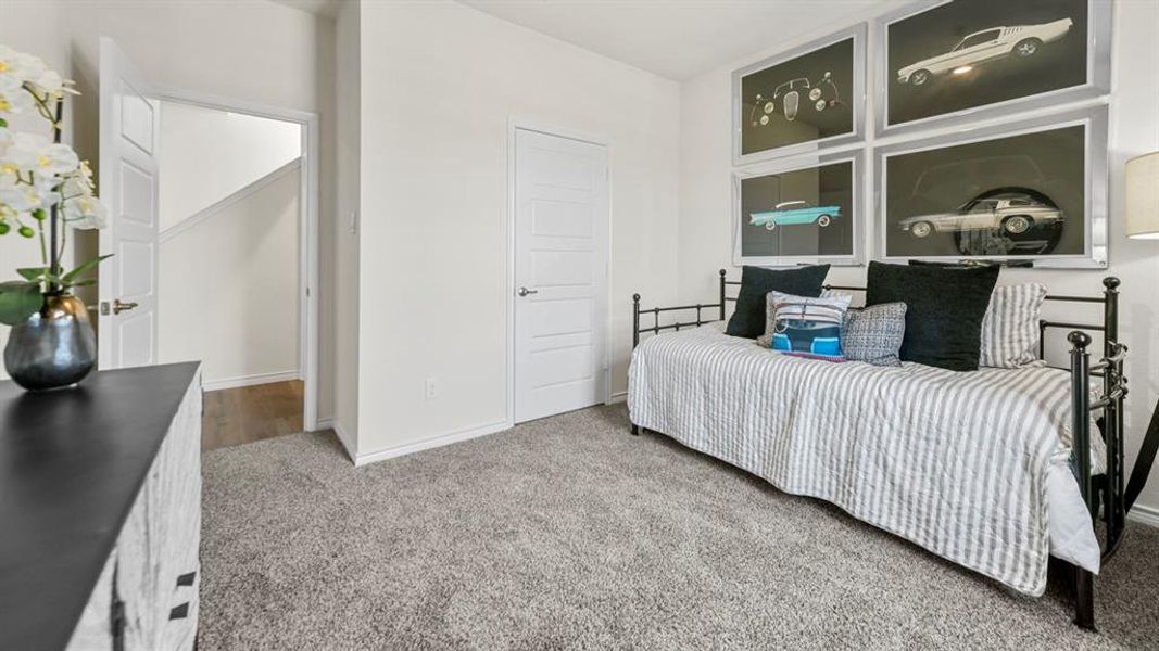 Carpeted room featuring a white paneled door and light-toned walls