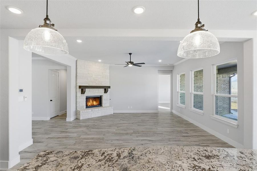 Unfurnished living room featuring a ceiling fan, light wood-style floors, a fireplace, and recessed lighting