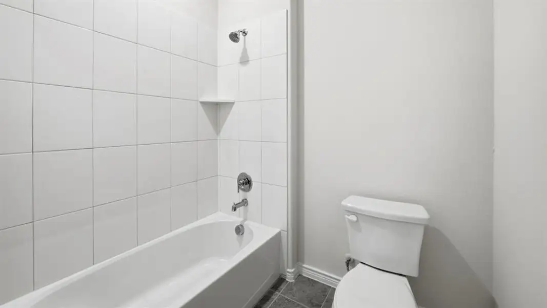 Full bath featuring shower / tub combination and dark tile patterned floors