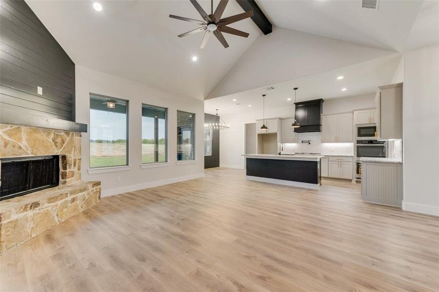 Unfurnished living room featuring high vaulted ceiling, beamed ceiling, ceiling fan, light wood finished floors, and recessed lighting Unfurnished living room featuring high vaulted ceiling, beamed ceiling, ceiling fan, light wood finished floors, and recessed lighting