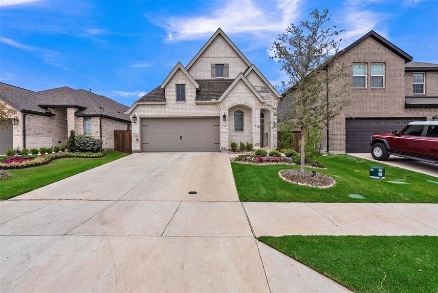 Two-story residence featuring a light-colored brick facade and dark-shingled gable roof Two-story residence featuring a light-colored brick facade and dark-shingled gable roof