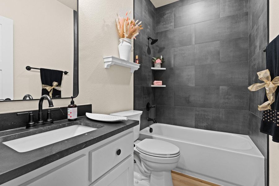 Bathroom with toilet, vanity, wood finished floors, and shower / bathtub combination Bathroom with toilet, vanity, wood finished floors, and shower / bathtub combination