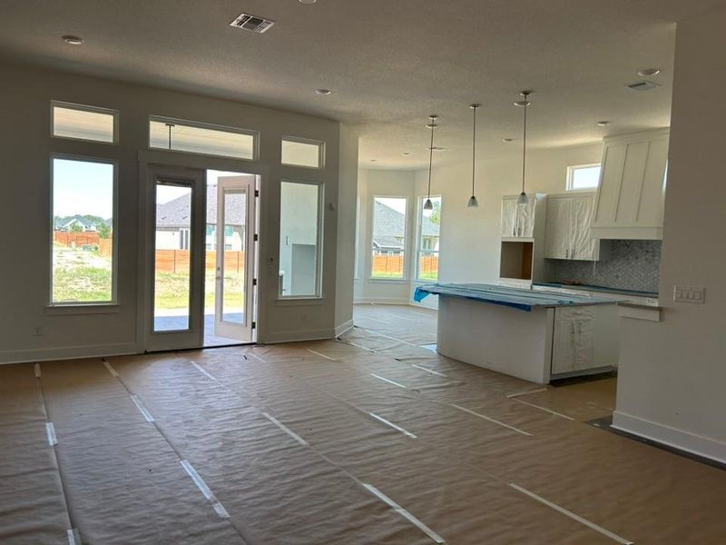 Kitchen with tasteful backsplash, white cabinetry, pendant lighting, a center island, and custom exhaust hood Kitchen with tasteful backsplash, white cabinetry, pendant lighting, a center island, and custom exhaust hood
