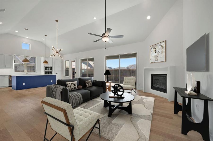 Living area with lofted ceiling, light wood-style floors, a glass covered fireplace, recessed lighting, and ceiling fan Living area with lofted ceiling, light wood-style floors, a glass covered fireplace, recessed lighting, and ceiling fan