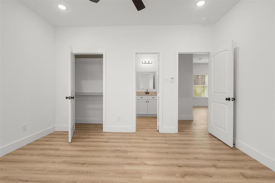 Unfurnished bedroom featuring ceiling fan, light wood-type flooring, and connected bathroom