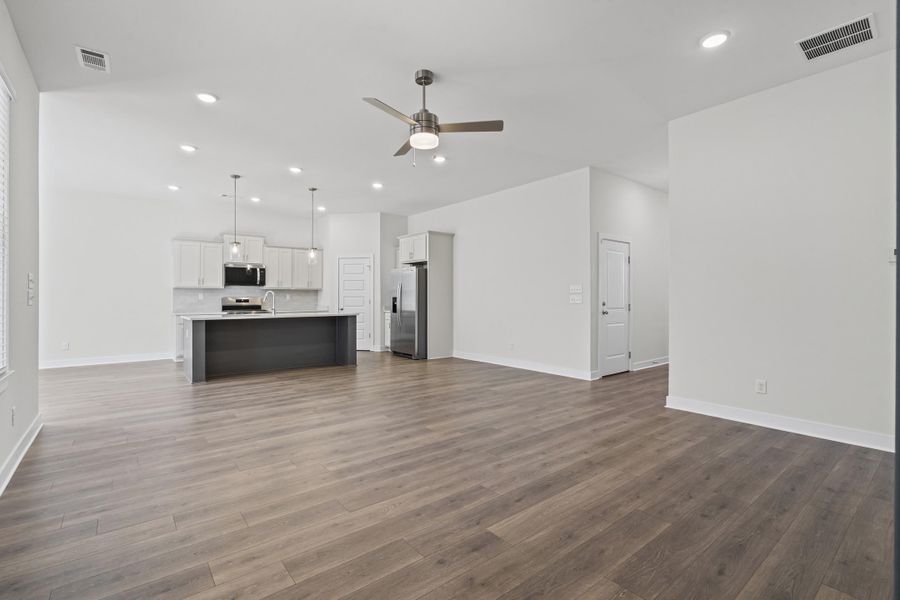 Unfurnished living room with a ceiling fan, recessed lighting, and dark wood finished floors