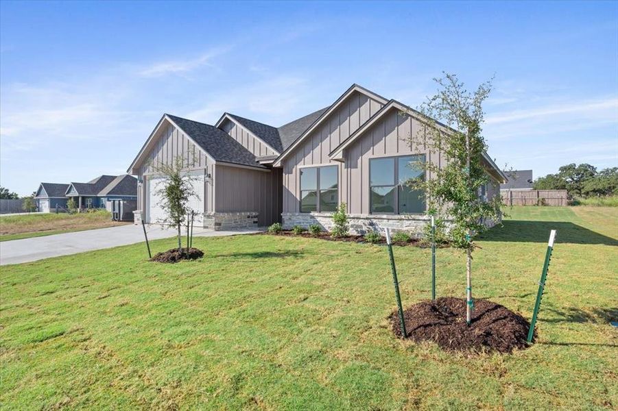 Modern farmhouse featuring board and batten siding, driveway, an attached garage, stone siding, and a shingled roof Modern farmhouse featuring board and batten siding, driveway, an attached garage, stone siding, and a shingled roof