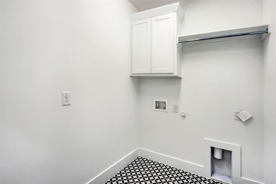 Laundry room featuring patterned floor tiling, crisp white walls, built-in cabinetry, and a clothing rod Laundry room featuring patterned floor tiling, crisp white walls, built-in cabinetry, and a clothing rod