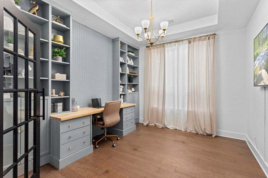 Office area with hardwood / wood-style flooring, a notable chandelier, and a tray ceiling