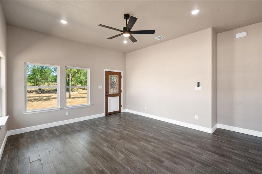 Open-concept living area featuring wood-finish flooring, recessed lighting, and a dark-toned ceiling fan