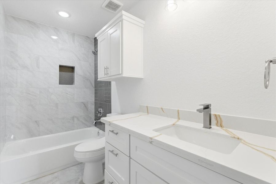 The ensuite full bath features a shower tub combo with sleek, modern finishes throughout. Quartz countertops and floor to ceiling decorative tile give you a clean, elevated look, creating a space that feels both polished and comfortable for everyday use. The ensuite full bath features a shower tub combo with sleek, modern finishes throughout. Quartz countertops and floor to ceiling decorative tile give you a clean, elevated look, creating a space that feels both polished and comfortable for everyday use.