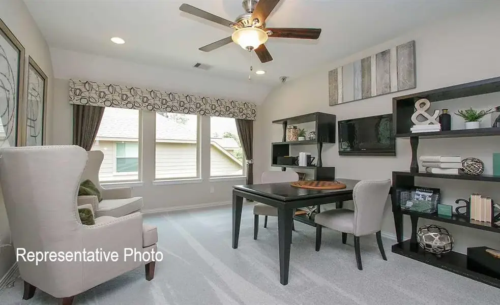 Carpeted office space with ceiling fan and vaulted ceiling